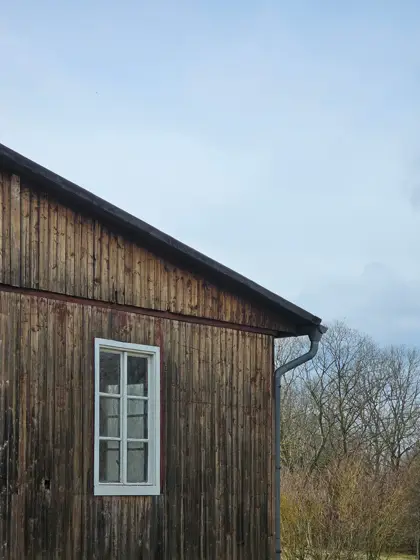 Tablas envejecidas y ventana blanca sobre el muro de madera.