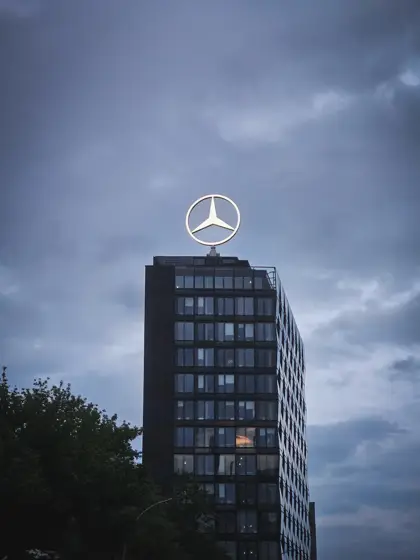 Torre de vidrio y emblema recortados bajo las nubes.