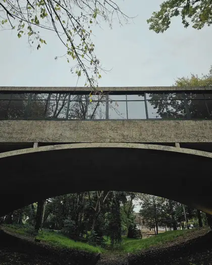 Casa del Puente: arco de hormigón y banda vidriada sobre el arroyo.