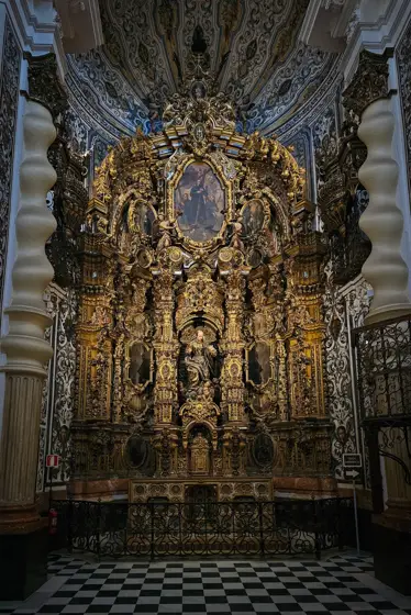 Un retablo dorado como fondo de una nave interior.