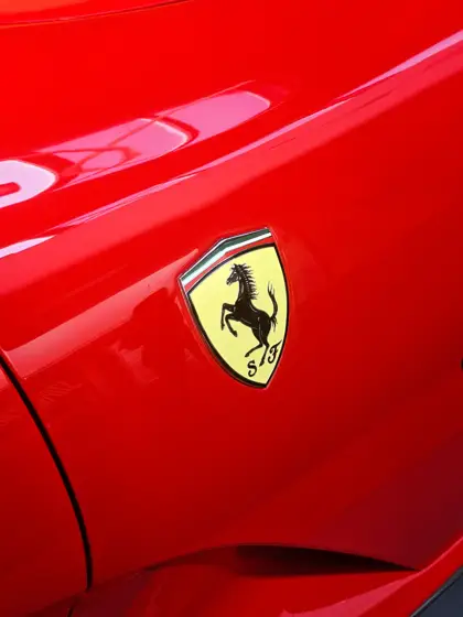 Emblema Ferrari y brillo de la pintura roja de la carrocería.