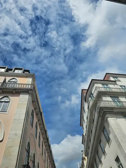 Dos fachadas próximas encuadrando el cielo y las nubes.