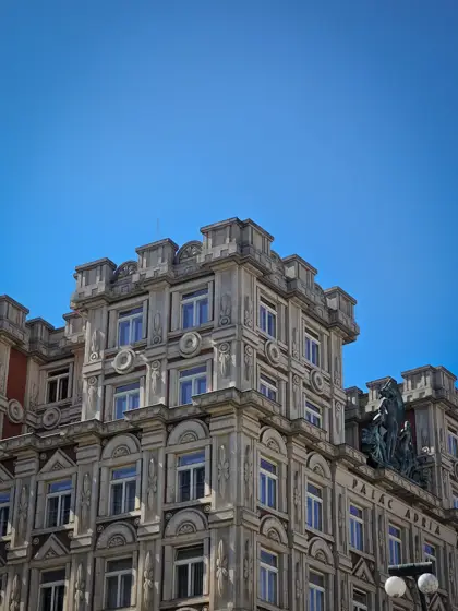 Una fachada de esquina de piedra con relieve y balcones.