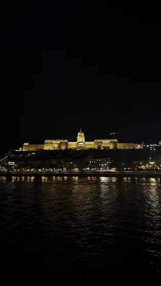 Una fachada iluminada reflejándose sobre el agua nocturna.