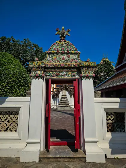 Puerta roja y ornamentación de piedra en el muro exterior.